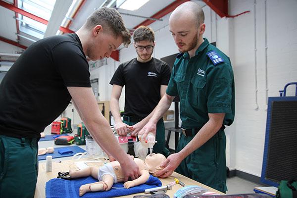 Paramedic students performing CPR on baby dummy