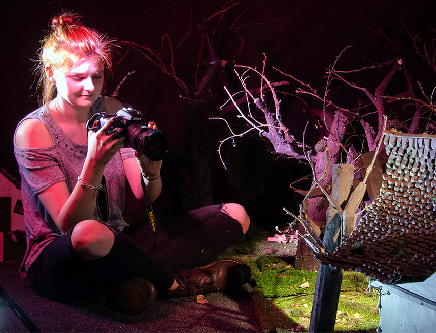 Student taking a photo of a miniature house