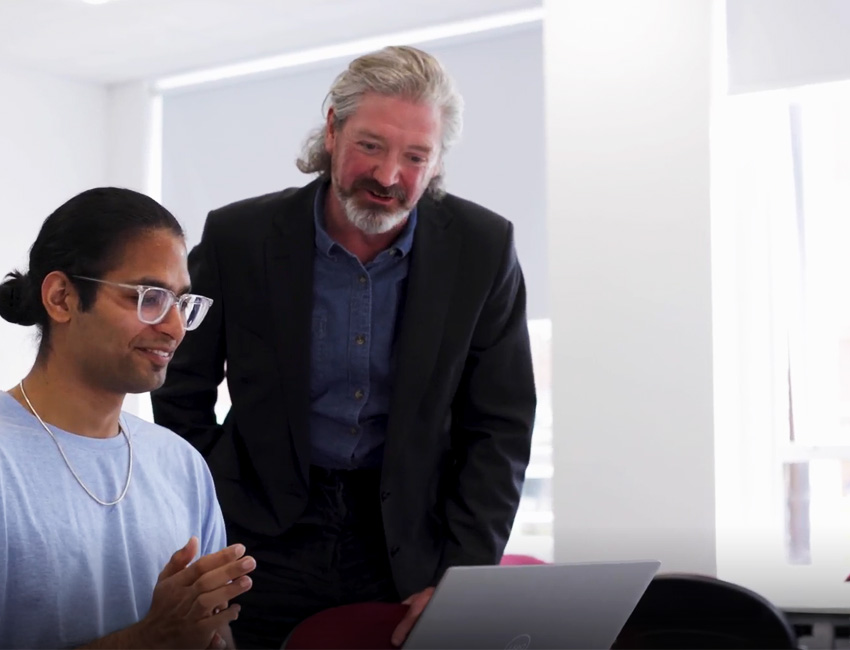 Lecturer working with a student at their laptop in a seminar