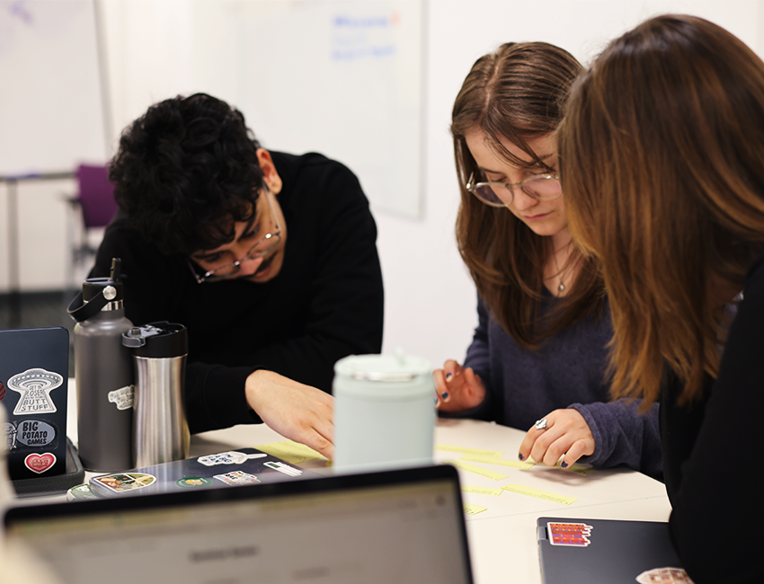 3 students in a classroom working on a written task together
