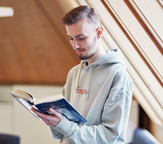 A student reading a book on historical revolutions in the Hive library