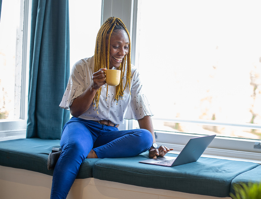 A student working on her laptop while drinking a cup of tea