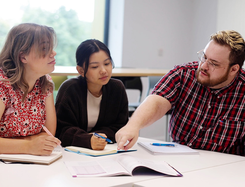Students in a classroom in discussion and taking notes.