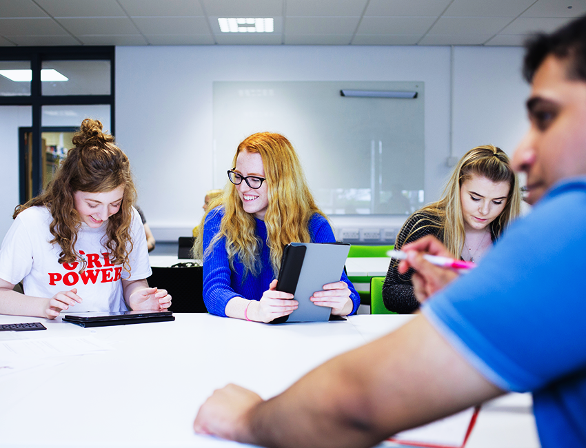 Students in a classroom taking notes on tablets. 