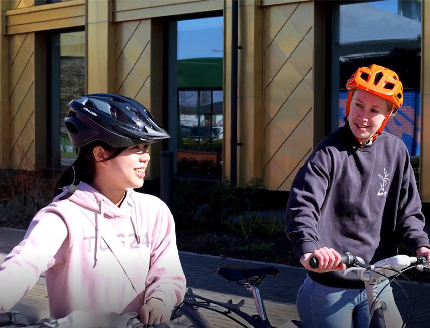 Students having a chat as they take their bikes to campus
