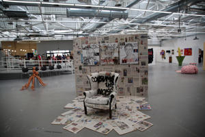 A chair coated in newspaper cuttings on a floor covered in newspapers