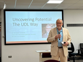 Dr Richard Jackson standing in front of a screen delivering a presentation called Uncovering Potential The UDL Way