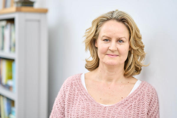 Jo Callaghan poses in a head and shoulders shot in a library next to a book shelf