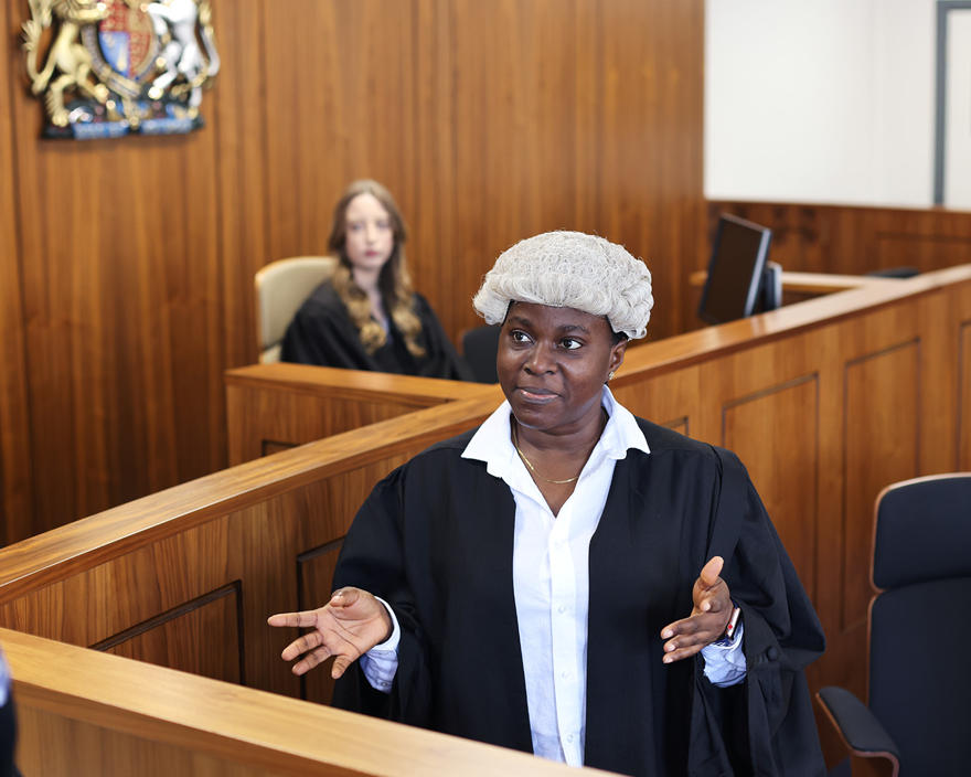 A law student wearing traditional black gown and white wig in the law court