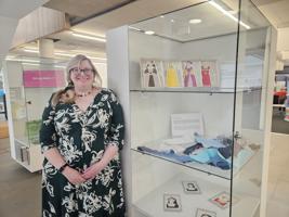 Lucie Bea Dutton poses next to a cabinet containing smaller stitchworks