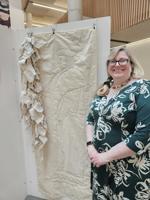 Lucie Bea Dutton poses next to stitchwork depicting the way people would address Cromwell in writing over the years