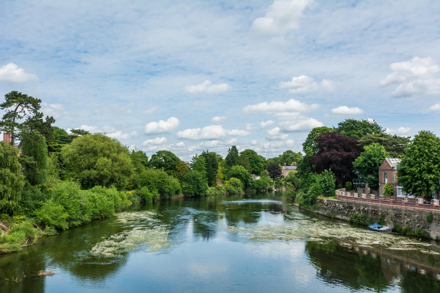Looking down River Wye as it flows through Hereford with trees reflected in the water