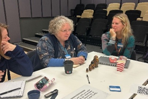 Three people sitting around a table engaged in Storytelling Activity based on Matryoshka (Russian) Dolls.