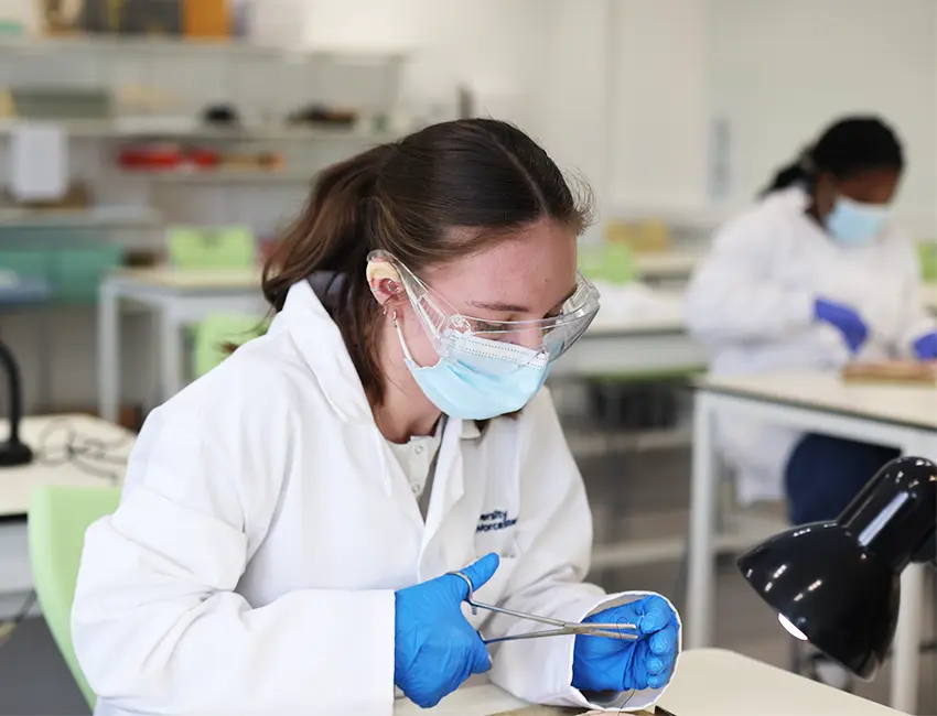 Students in labcoats and face masks working in a science lab