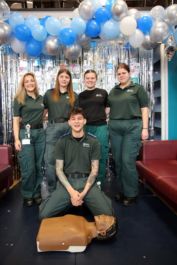 Paramedic students pose around a dummy