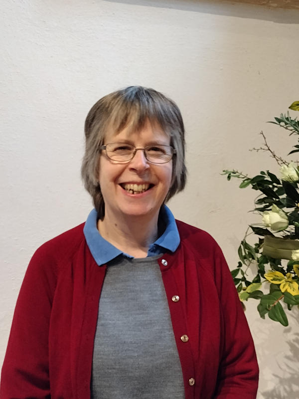 Catherine Lack of the Interfaith Forum poses indoors next to some flowers