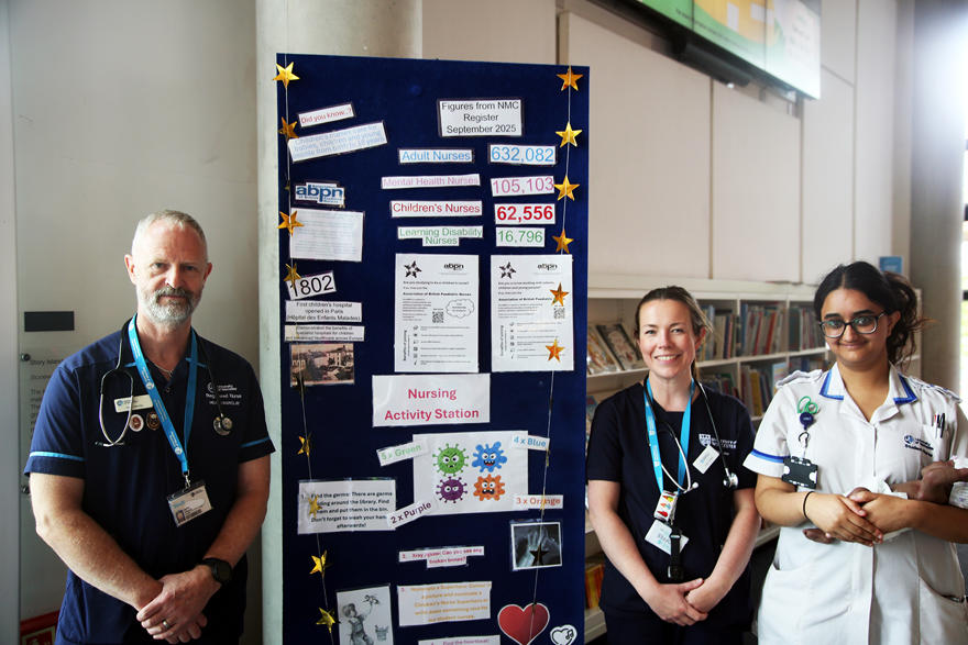 Staff and students pose next to an educational display about children's nursing in The Hive