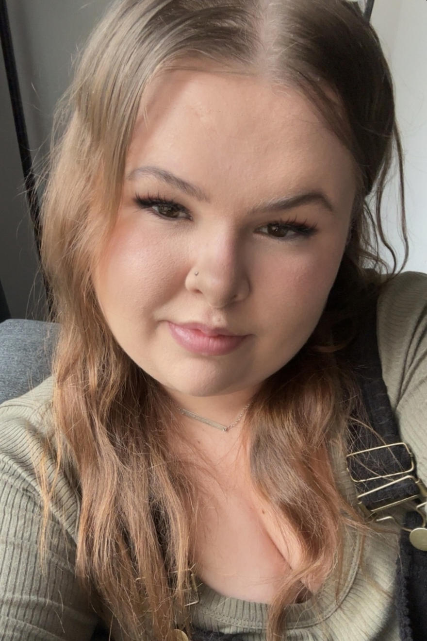 Chloe Cadwallader poses in a green top with dark coloured dungarees.