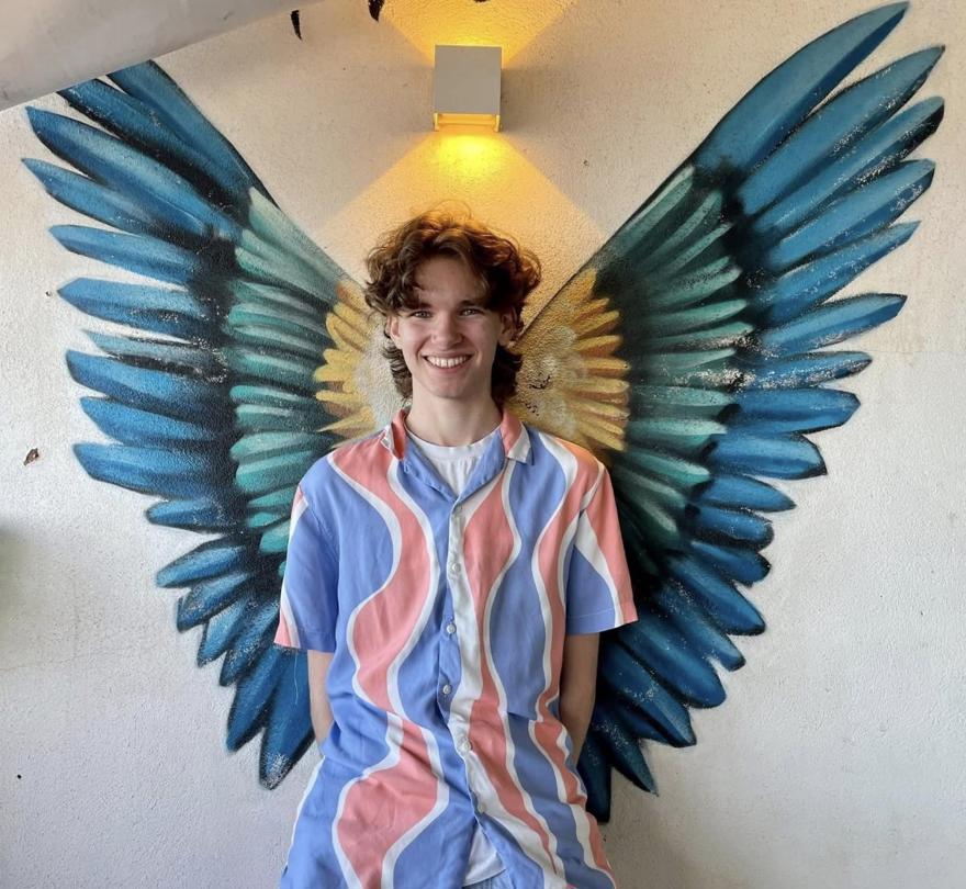 A student poses in front of angel wings wall art