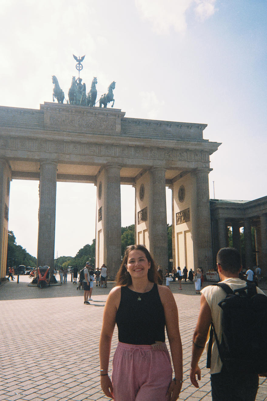 A student poses in front of a courtyard with an archway in the background