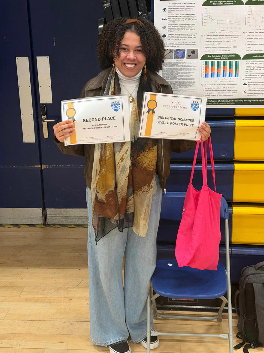 A student poses while holding up two certificates