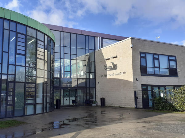 The Hereford Academy under a blue sky with rain on the ground