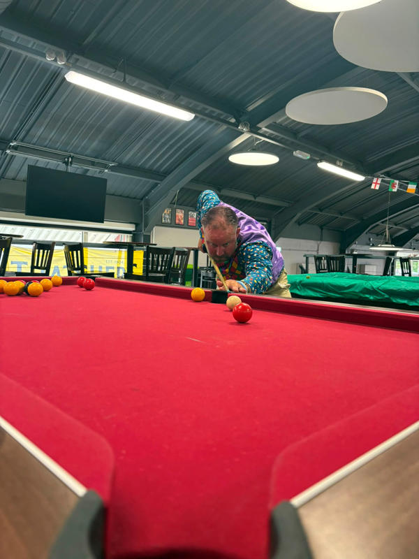 Ian Alley prepares to take a shot on a red pool table