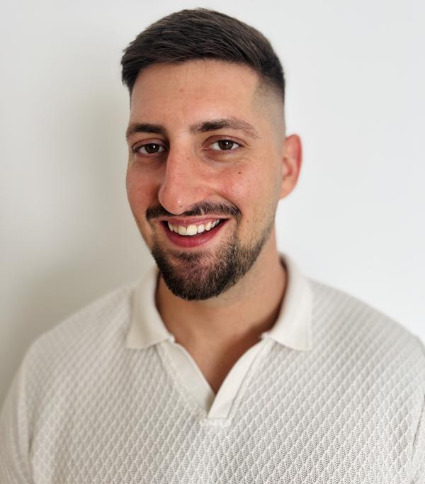 A portrait shot of Iskren, smiling, wearing a white shirt against a white background