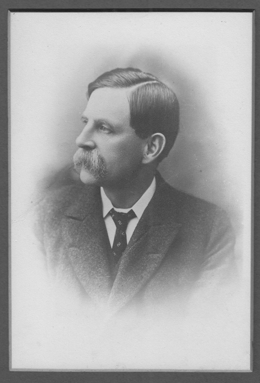 A black and white image of Lionel Stretton in a suit looking away from the camera