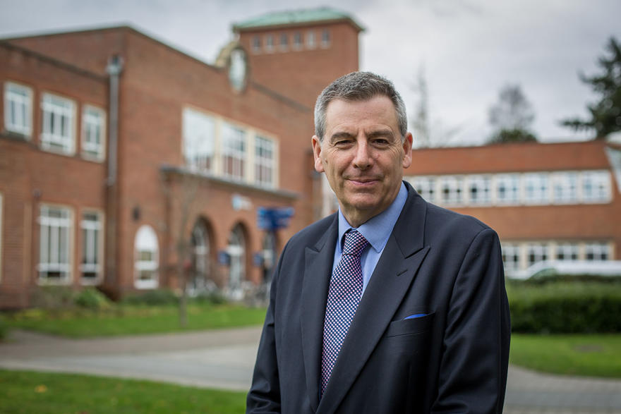 Professor David Green poses in a suit outside the main reception at the University of Worcester
