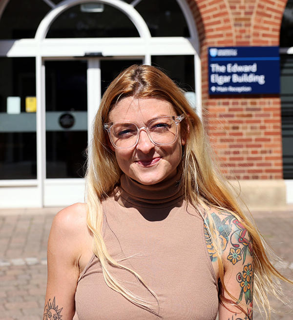 Rachael Ashton smiling at the camera by the University of Worcester's main entrance