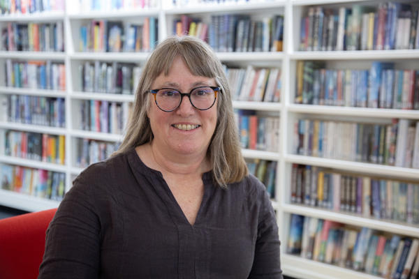 Dr Young poses looking at the camera in a library setting