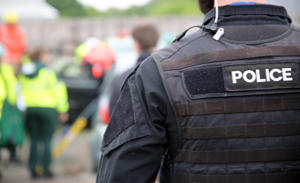 A close up of a policeman's vest as he looks at the scene