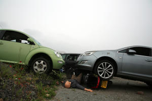 Cars arranged in a collision state with one car on top of a crashed motorcycle