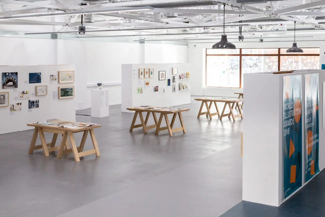 Art House interior. White room with three art display boards and three desks with students art work.