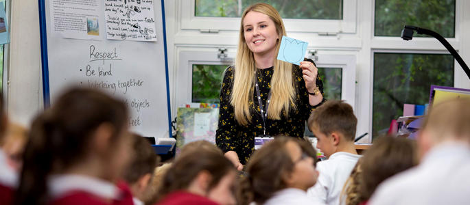 A female teacher training student in a classroom working on placement as part of her degree to get into teaching.