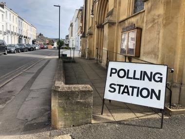 A polling station sign outside of a old building