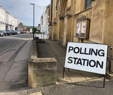 A polling station sign outside of a old building