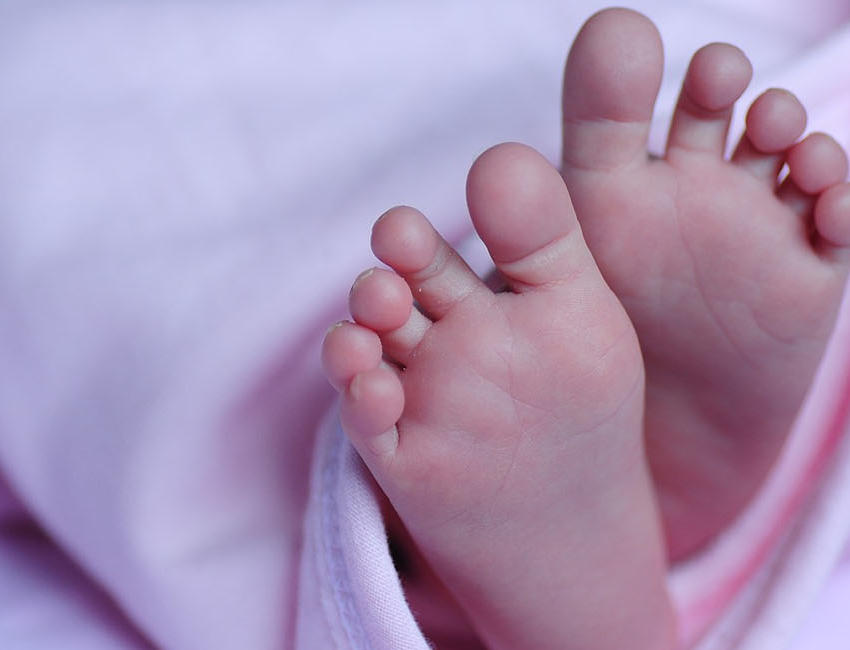 A close up of a baby's feet. The baby is wrapped in a pink blanket.