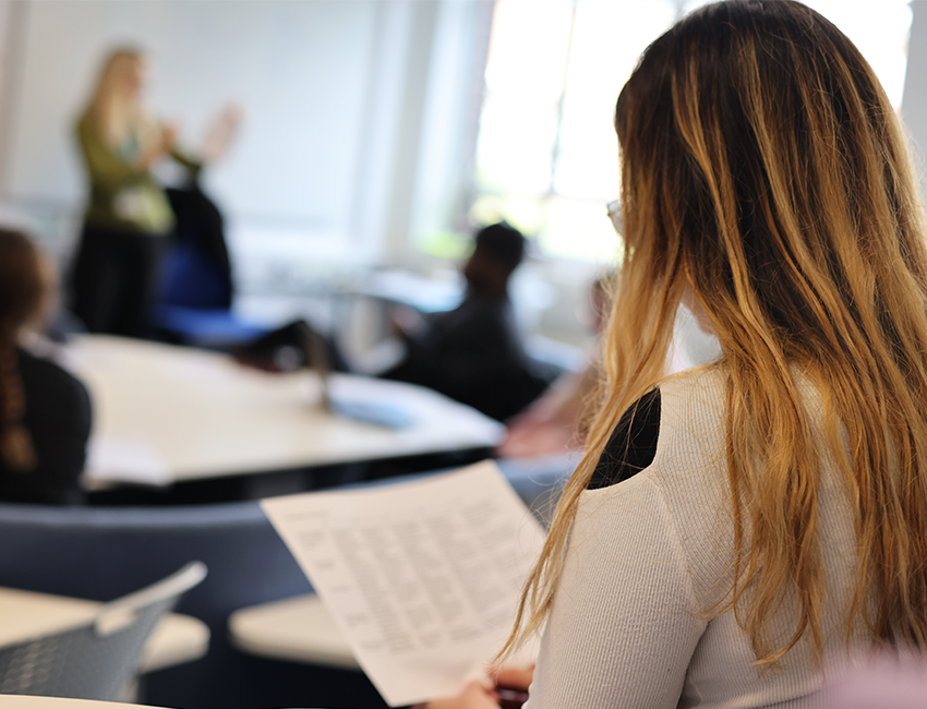 A student reading as a lecturer leads a class