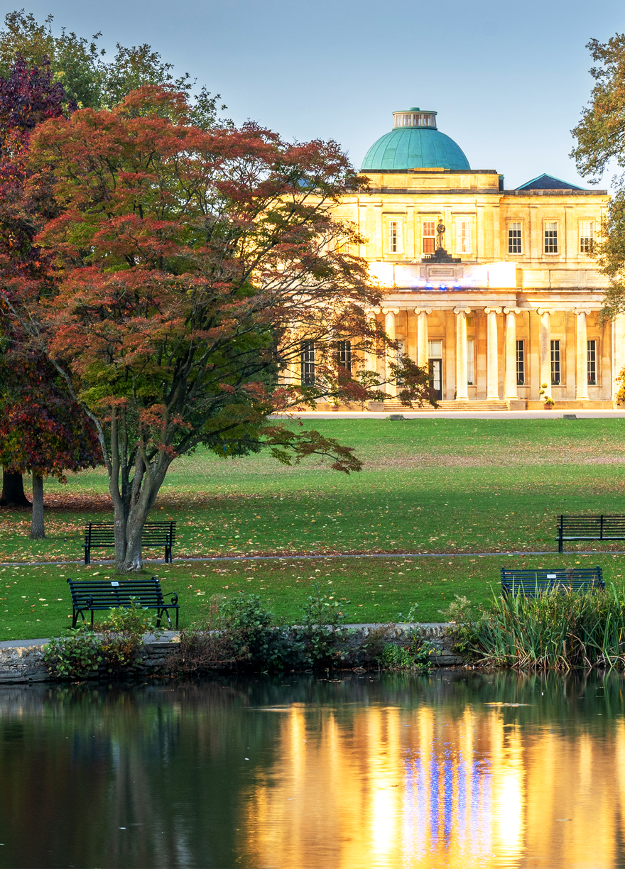 Historic building in a garden with trees and a lake