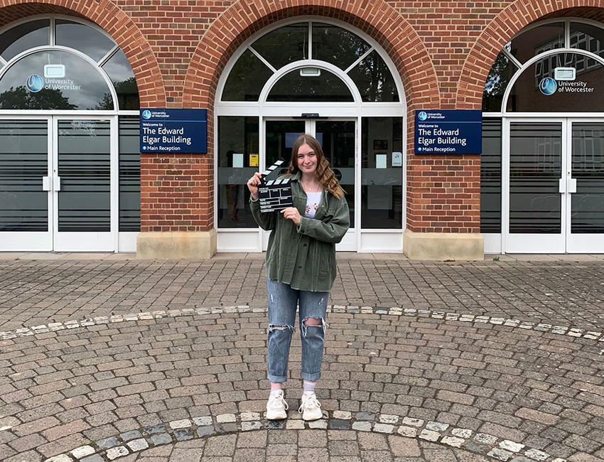 Ellie stood outside main reception with a clapperboard