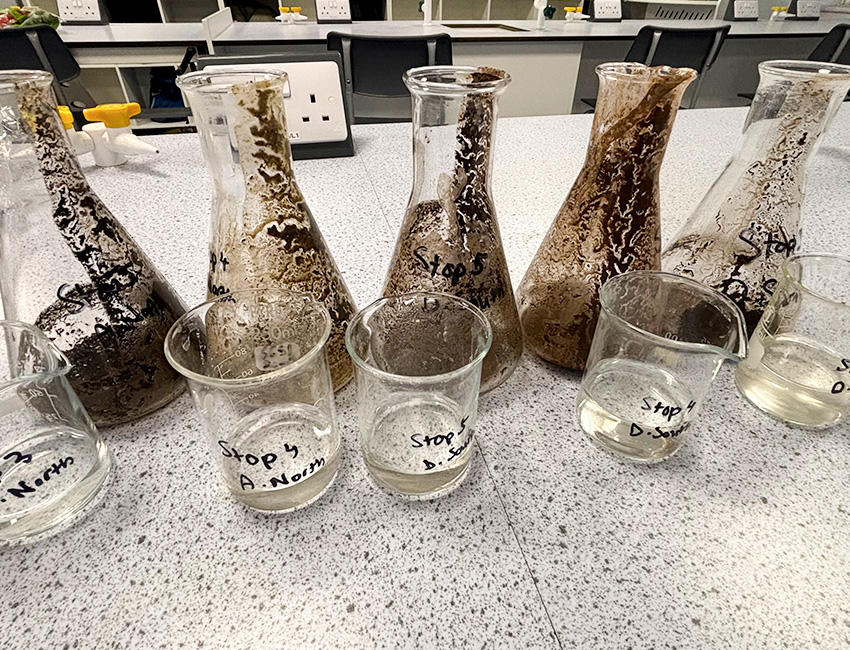 Soil in labelled tubes with jars of acid on a workstop in a lab