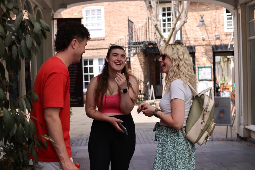 Three students are laughing in a courtyard area in the city