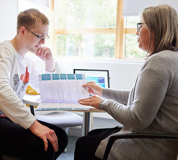 A female member of staff is assisting a male student