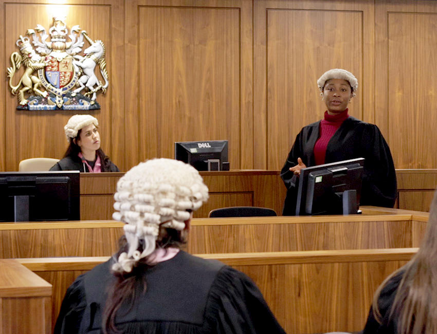 Law students during a mock court trial, with one student stood and addressing the room