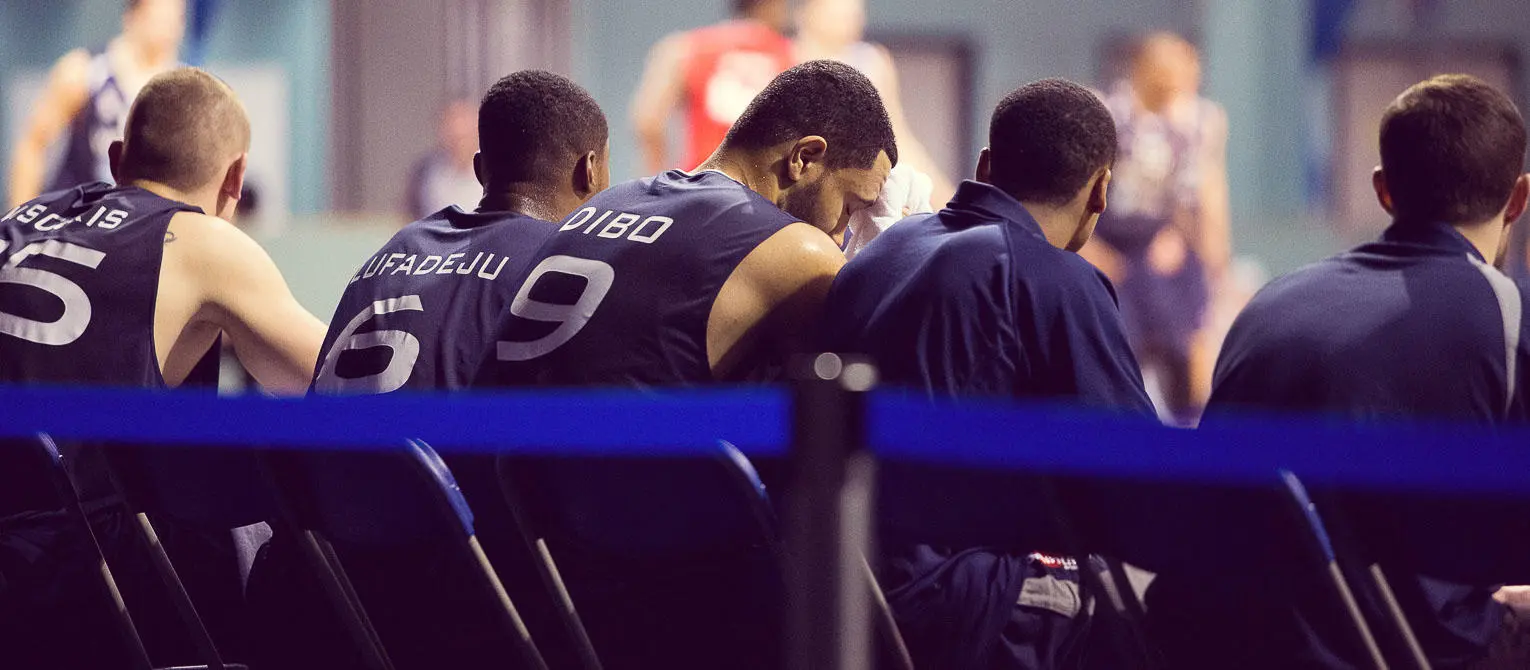 Basketball team sat on bench.
