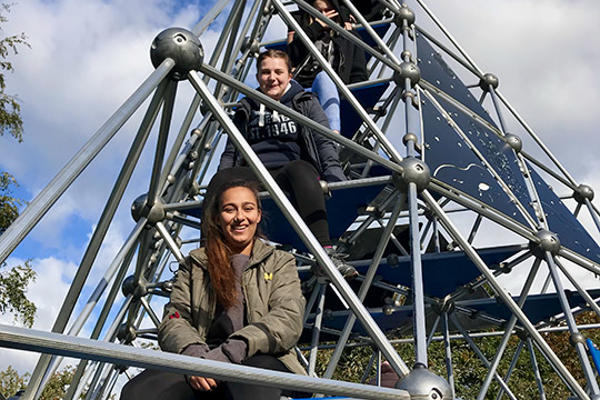 Students sit on pyramid climbing frame
