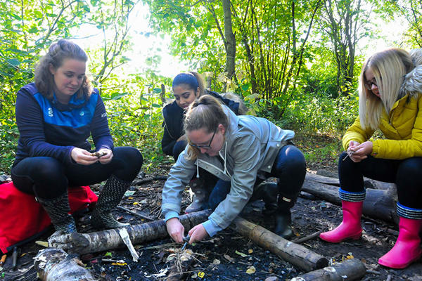 Early Childhood in Society students sat in forest, learning how to build a fire