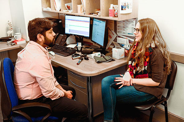 2 students sat at computer desk facing each other